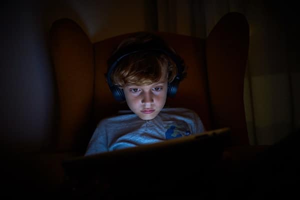 boy playing video games on tablet in the dark room