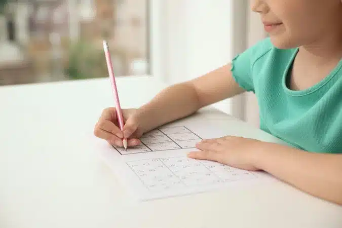 Little girl solving sudoku puzzle